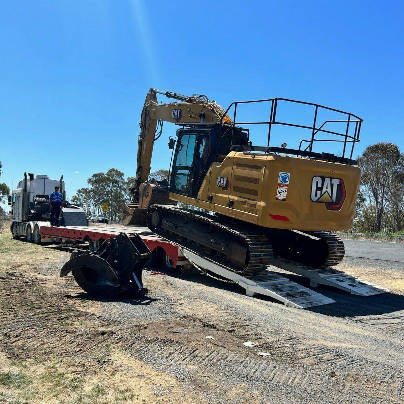 A Cat Excavator Is Being Towed by A Semi Truck — RC Civil in Armidale, NSW