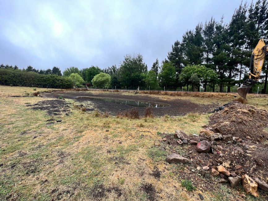 A Yellow Excavator Is Digging a Hole in The Middle of A Field — RC Civil in Armidale, NSW