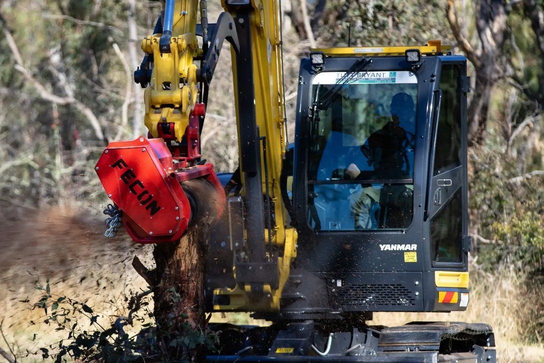 A Man Is Driving a Yellow and Black Excavator in A Forest — RC Civil in Armidale, NSW