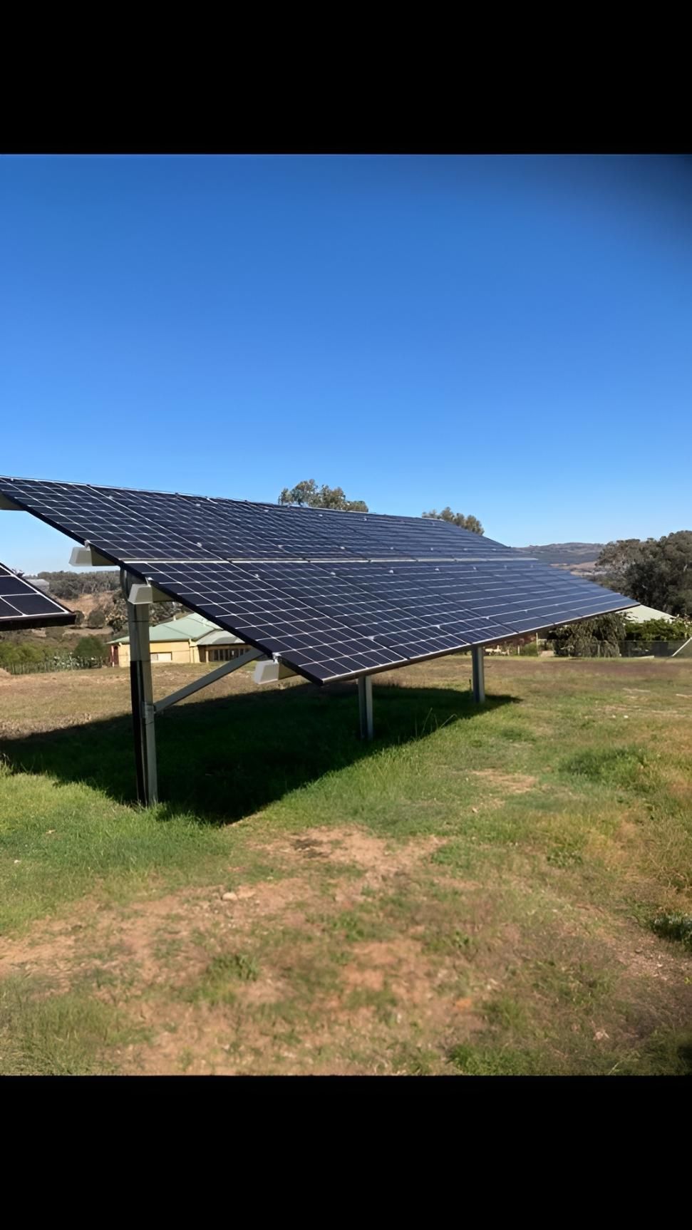Solar Panel Array on Green Grass Under a Blue Sky — Todd Basham Electrical in Cootamundra, NSW