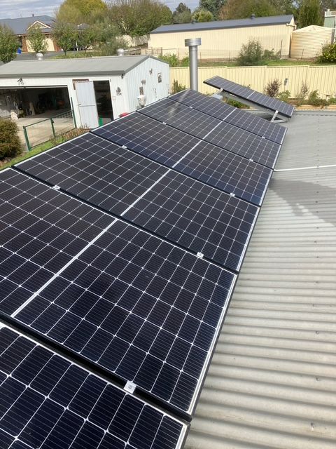 Solar panels installed on a corrugated metal roof in an outdoor setting. — Todd Basham Electrical in Harden, NSW