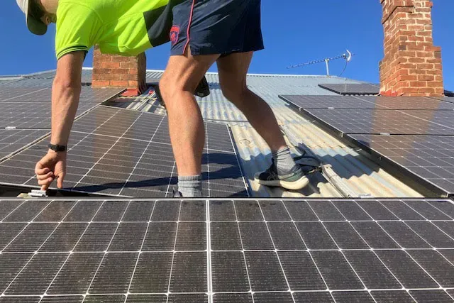 A Man Installing Solar Panels on a Metal Roof — Todd Basham Electrical in Cootamundra, NSW