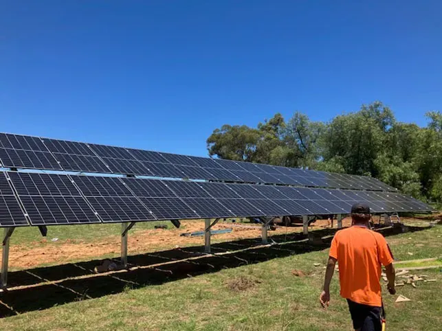 A Man Installing Solar Panels in a Field— Todd Basham Electrical in Harden, NSW