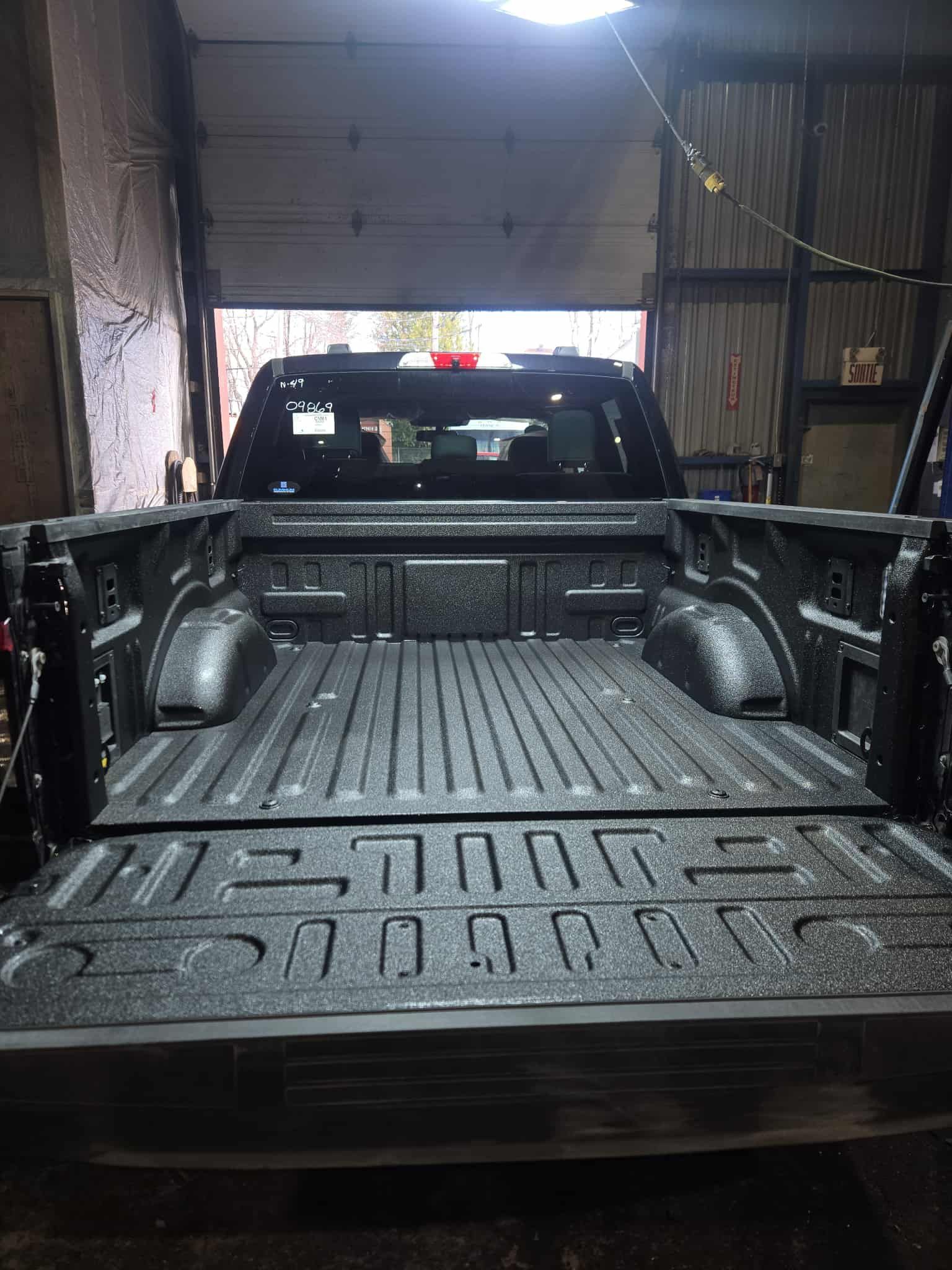 Plateforme de camionnette noire, porte de garage ouverte en arrière-plan.