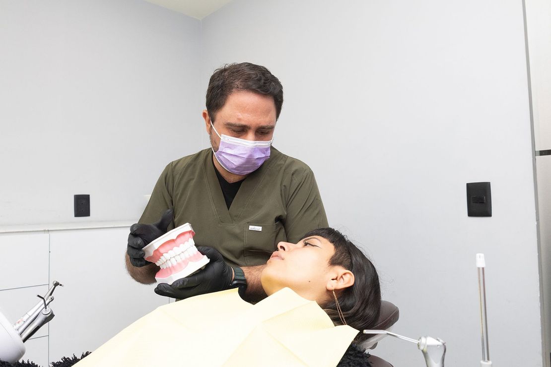 Un dentista está examinando los dientes de un paciente en una silla dental.
