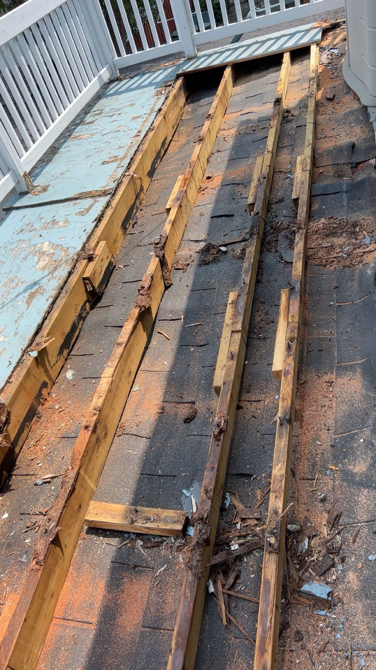 Terrasse déconstruite; poutres en bois pourries et matériau de toiture noir.