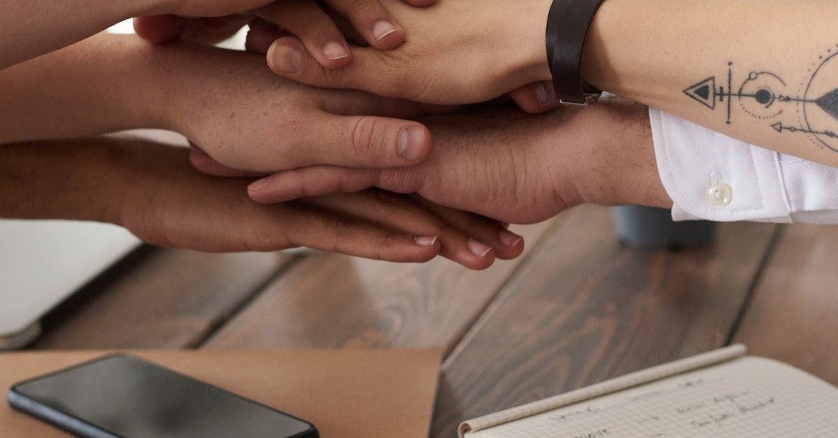 A group of people are putting their hands together to show support for one another.