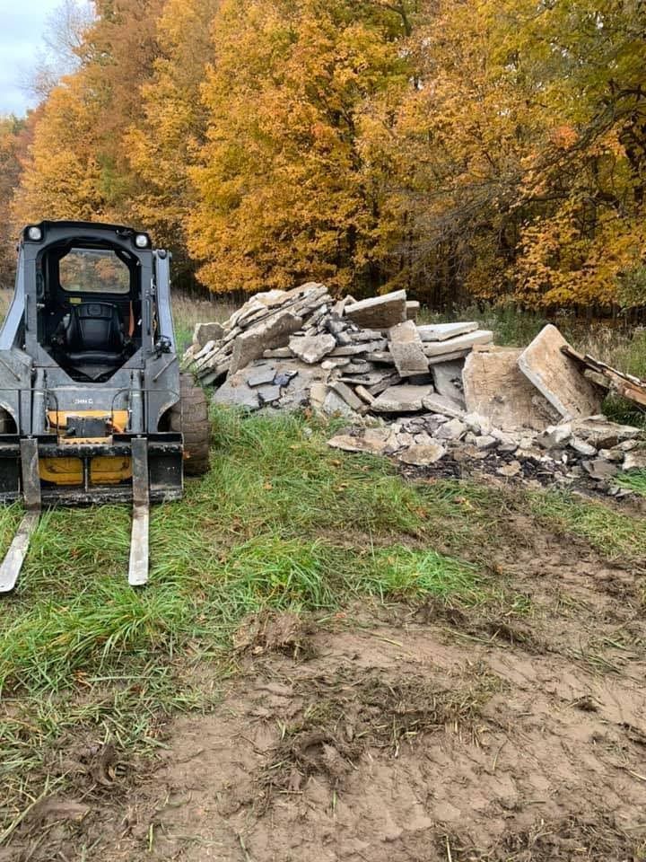A bulldozer is sitting in a field next to a pile of rocks.