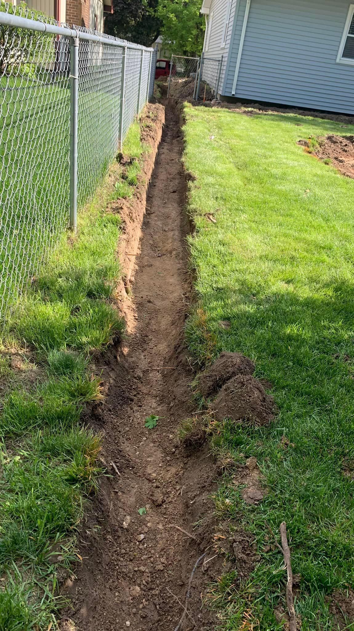A dirt path leading to a house next to a chain link fence.