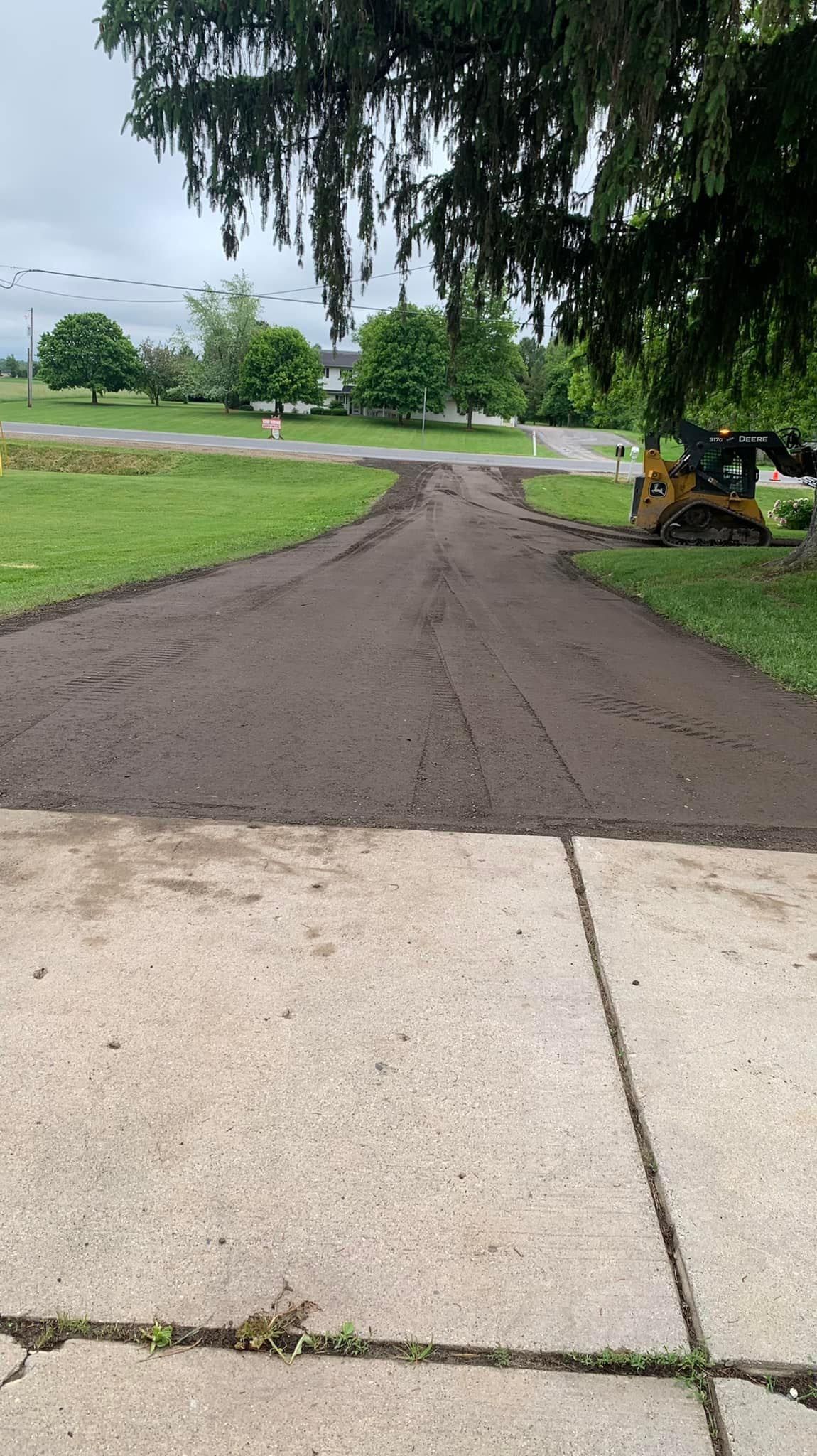 A dirt road going through a grassy field next to a sidewalk.