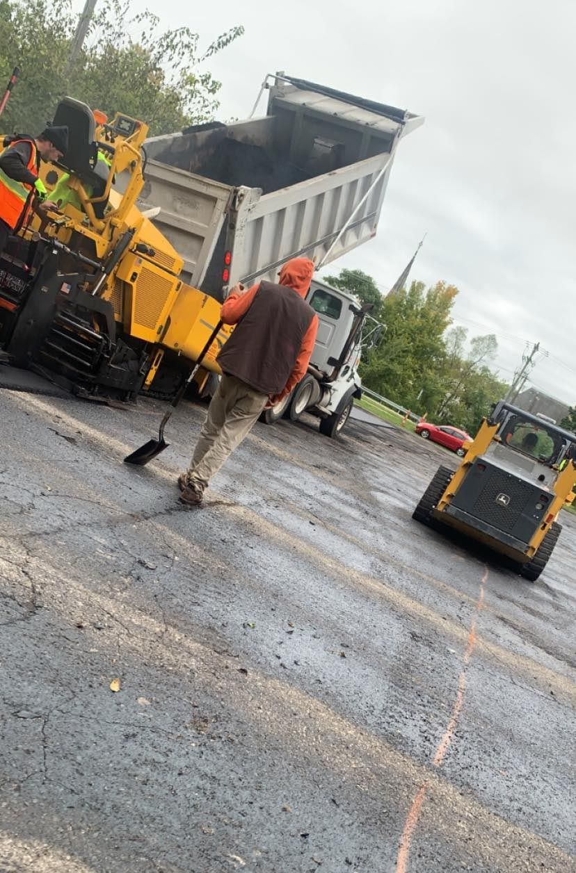 A man is standing next to a dump truck in a parking lot.