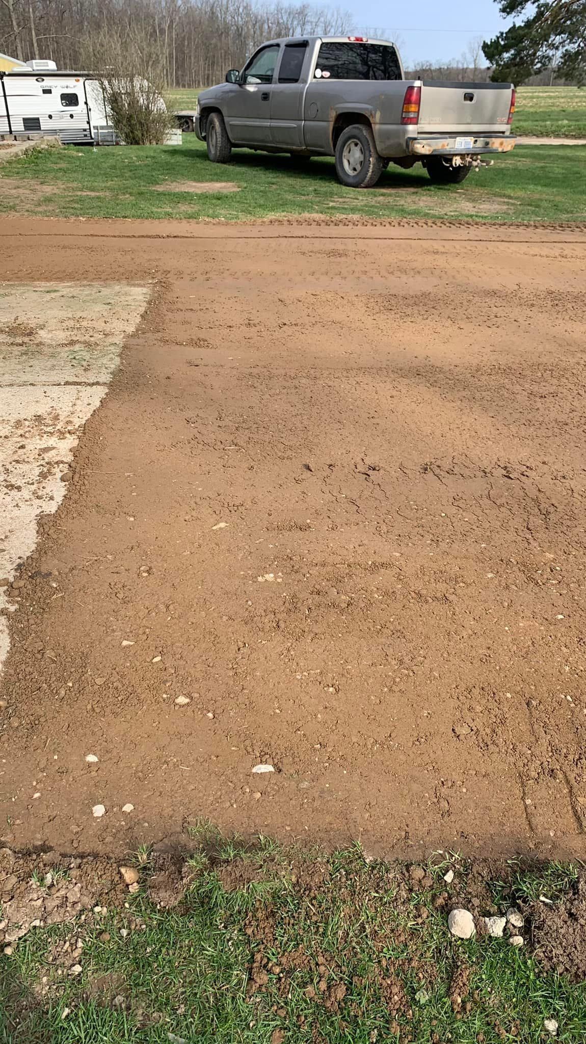 A truck is parked on the side of a dirt road.