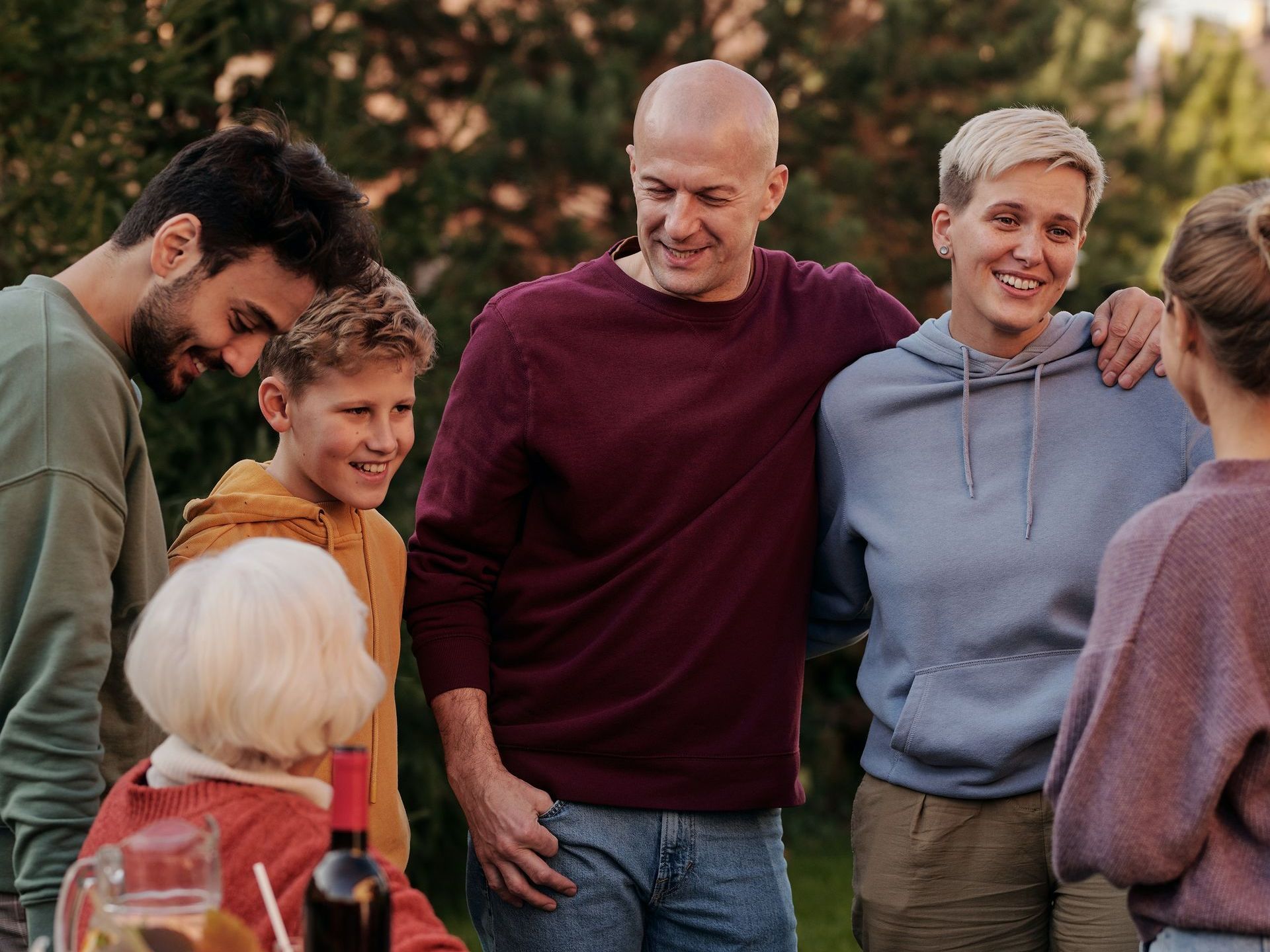 A group of people are standing around a table talking to each other.