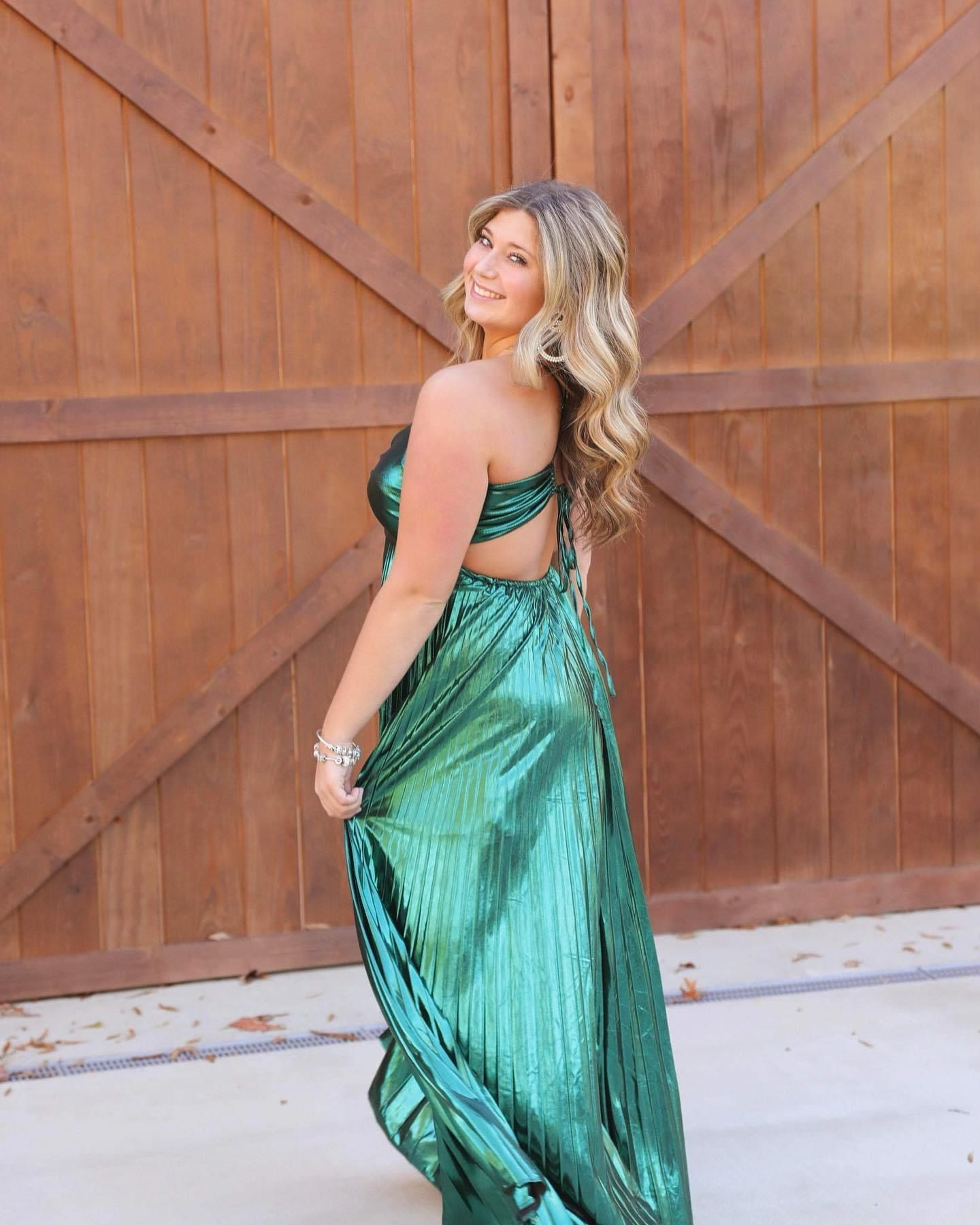 A woman in a green dress is standing in front of a wooden door.