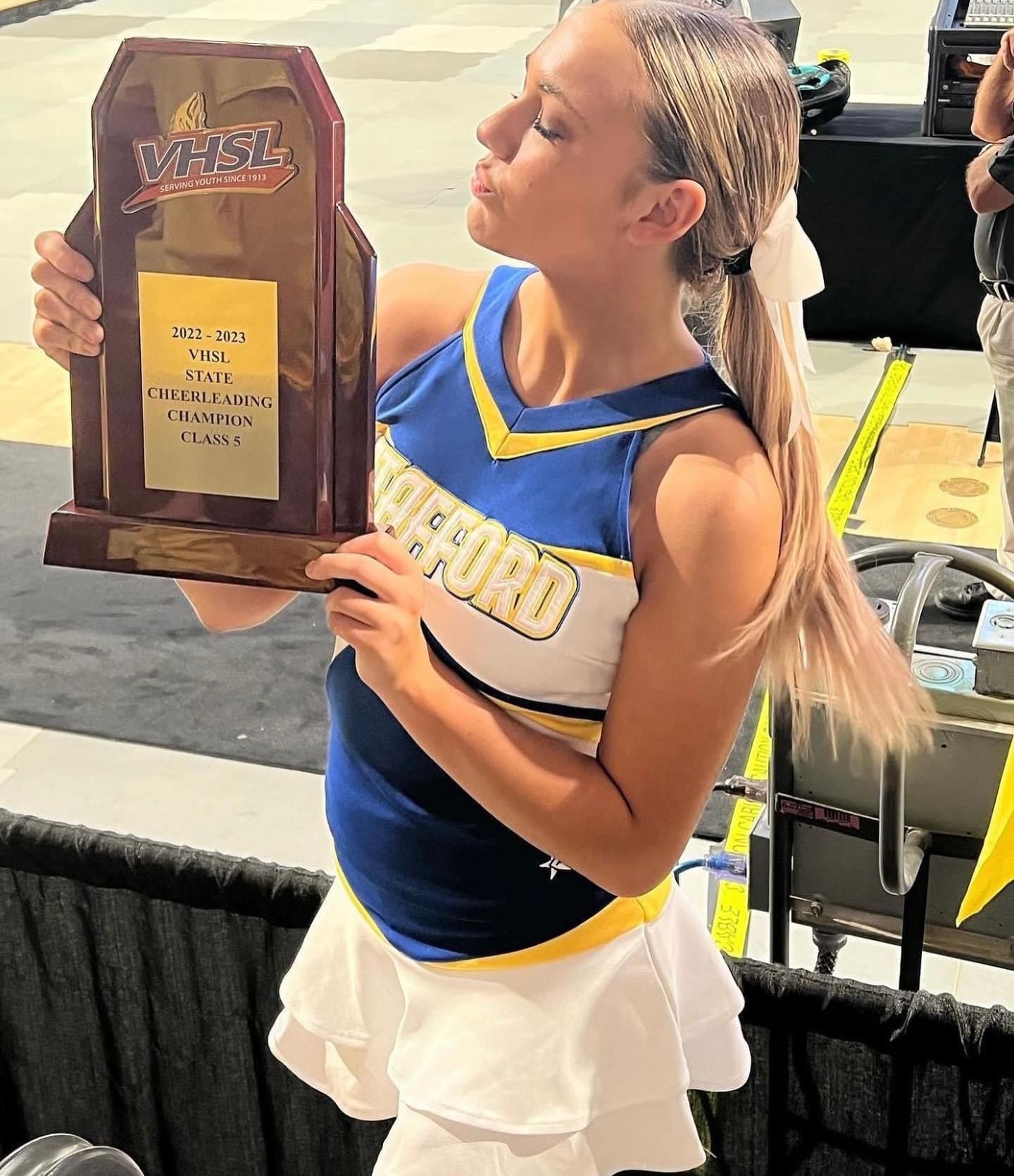 A cheerleader is holding a trophy that says west