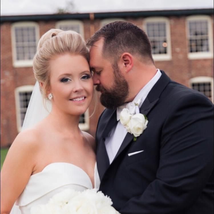 A bride and groom are posing for a picture in front of a brick building