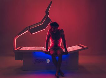 A man is sitting on a bed with red and blue lights on it.