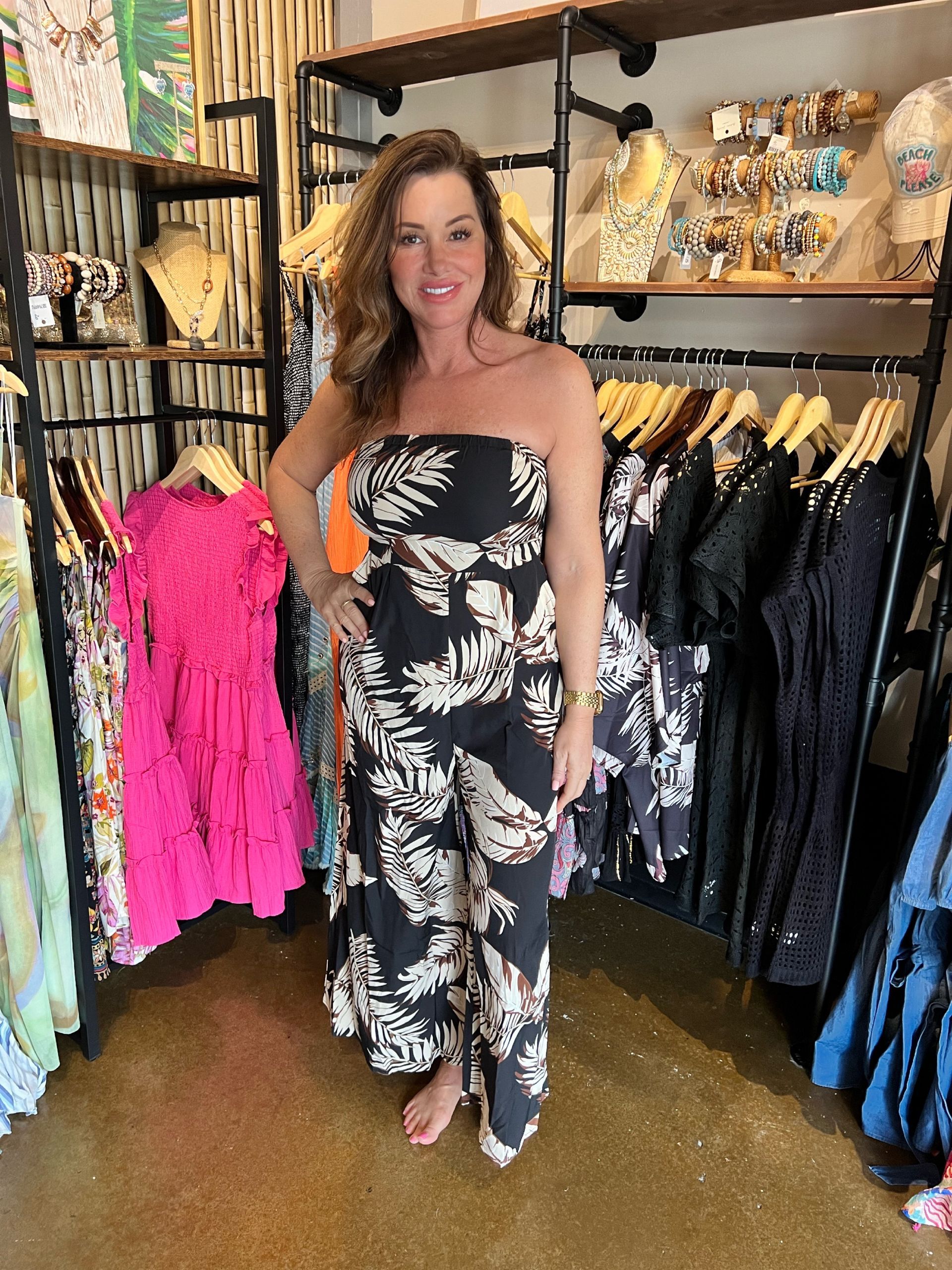 A woman in a strapless jumpsuit is standing in a clothing store.