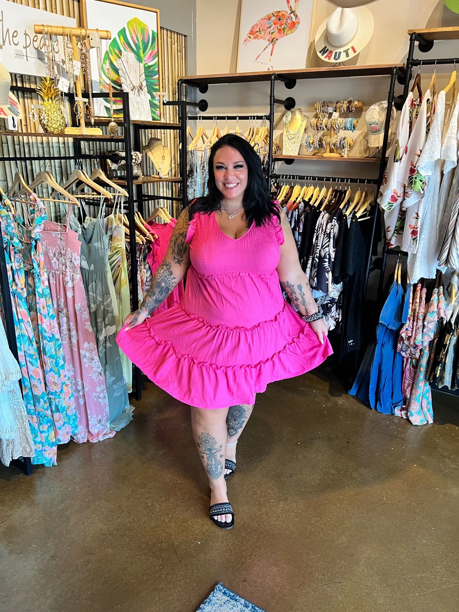 A woman in a pink dress is standing in a clothing store.