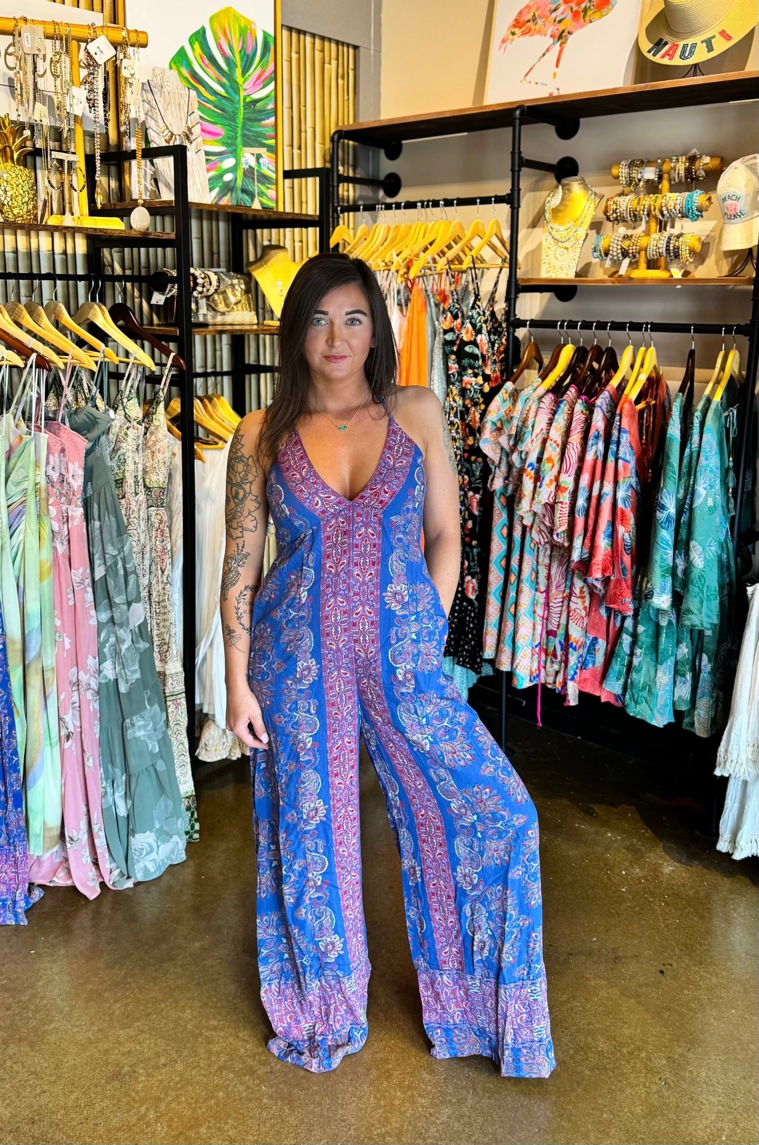 A woman is standing in a clothing store wearing a blue jumpsuit.