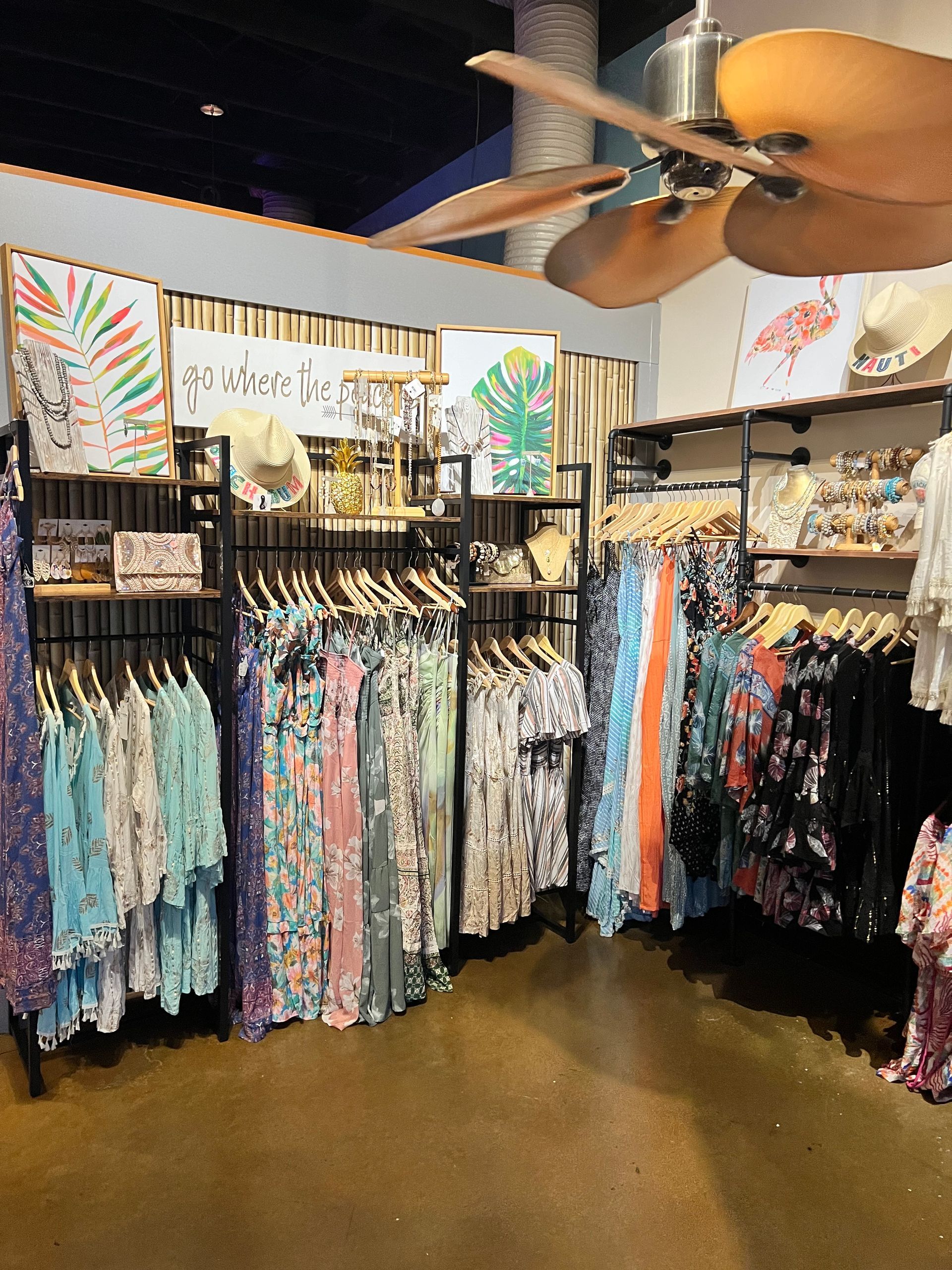 A store filled with lots of clothes and a ceiling fan.