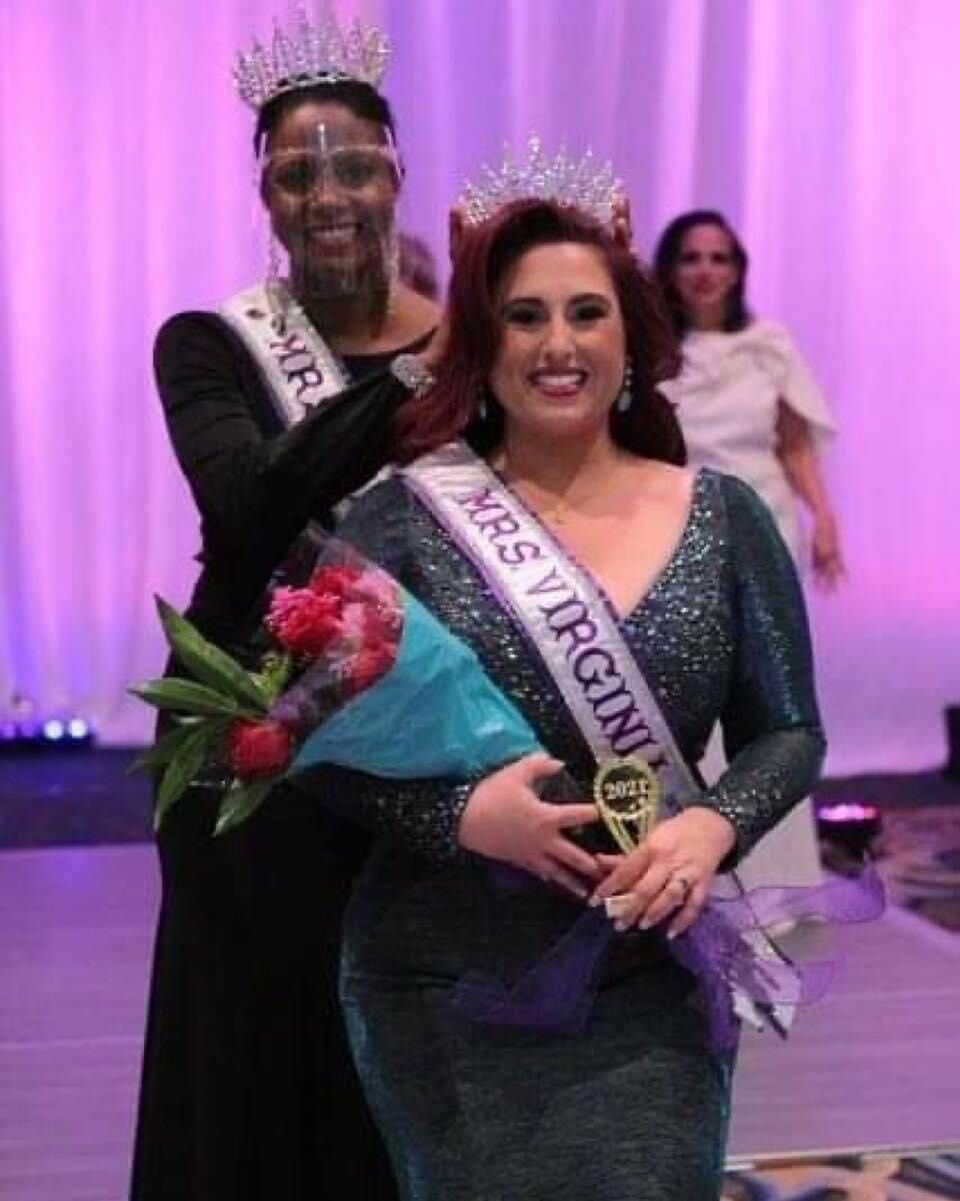 A woman is holding a bouquet of flowers and wearing a sash that says mrs virgini