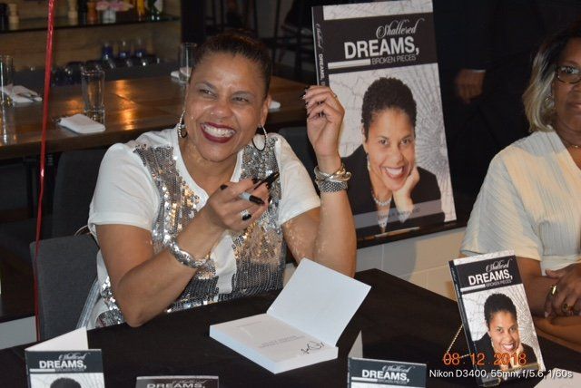 A woman sitting at a table holding a book titled dreams