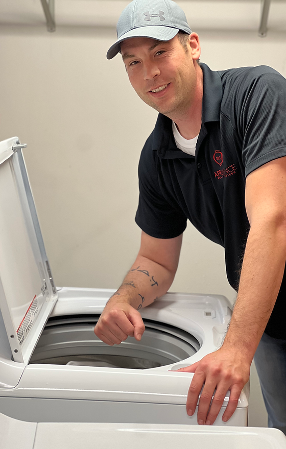 A man is standing next to a washing machine with the lid open.