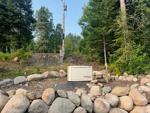 A generator is sitting on top of a pile of rocks in the middle of a forest.