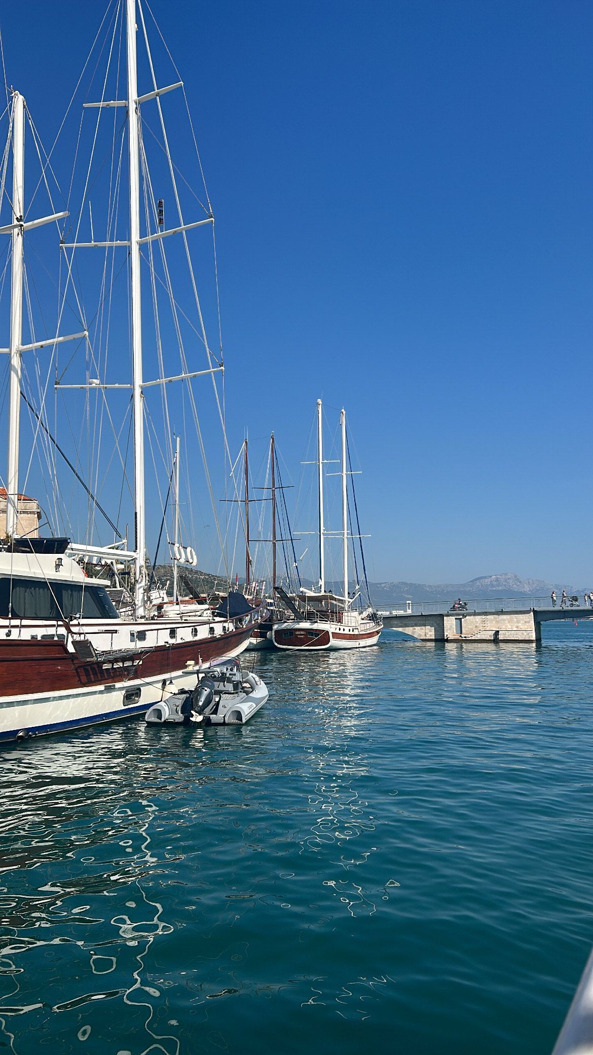 Sailboats docked in a harbor in Croatia with clear blue water and sky.