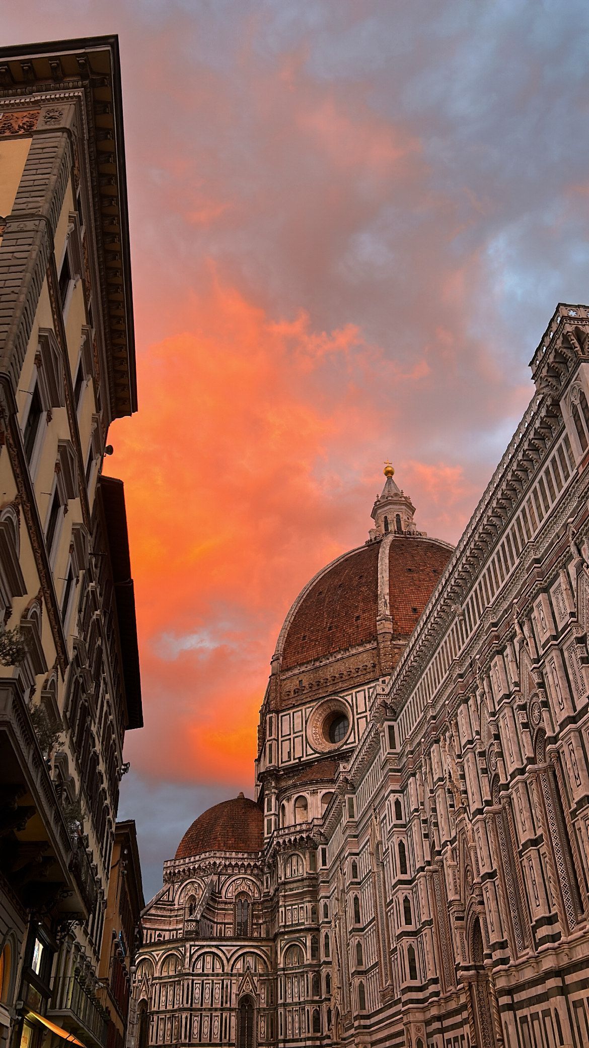 Florence, Italy buildings against an orange and blue sunset sky.