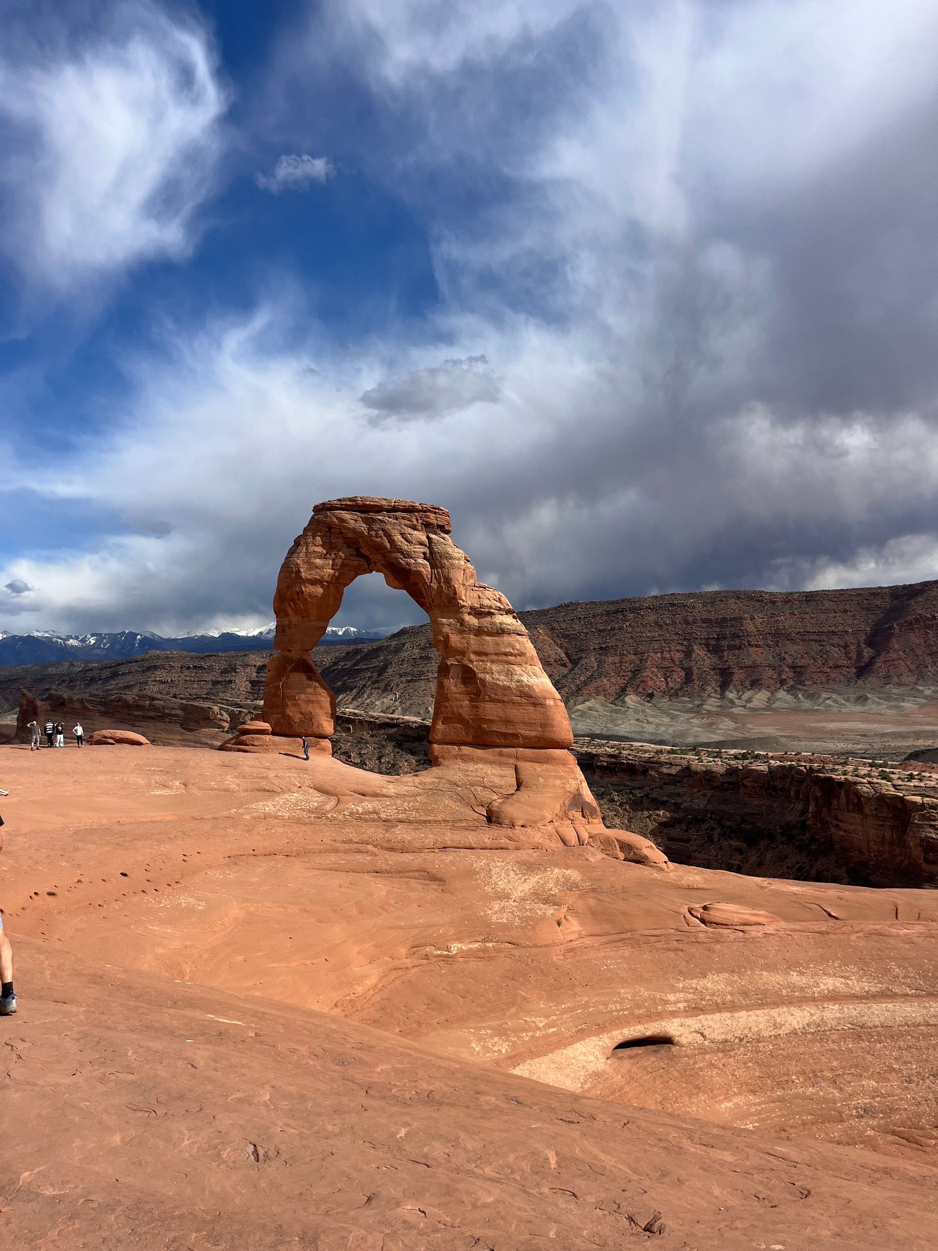 Delicate Arch in Arches National Park, Utah; red sandstone arch against a cloudy blue sky.
