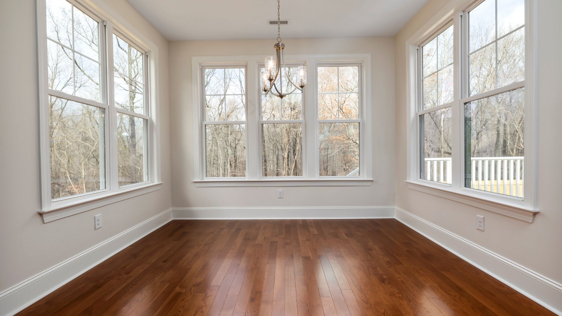 An empty room with hardwood floors and lots of windows.