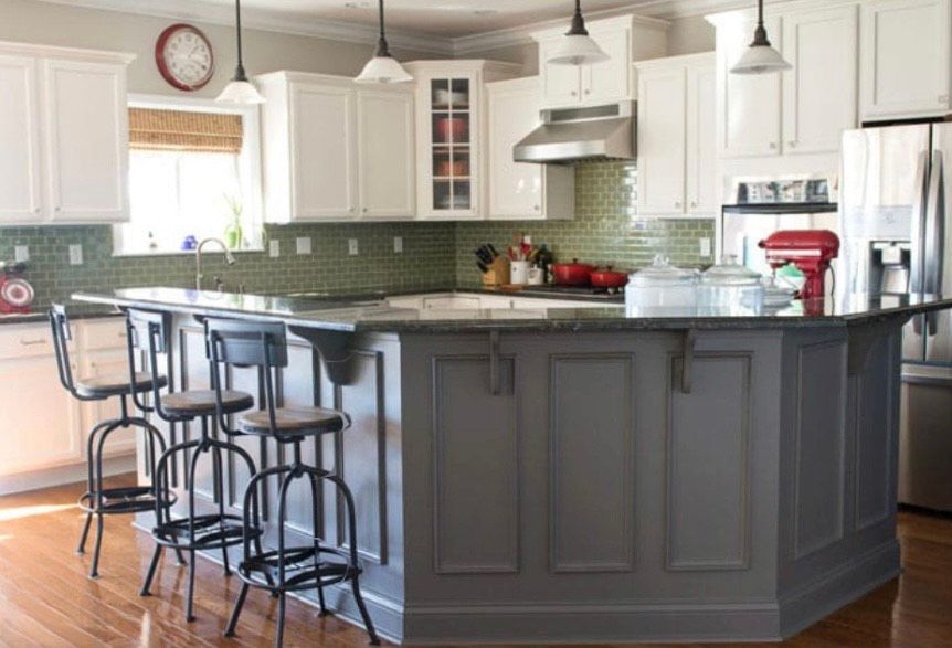 A kitchen with white cabinets and a large island with stools.