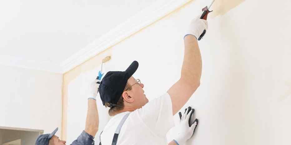 Two men are painting a wall together.