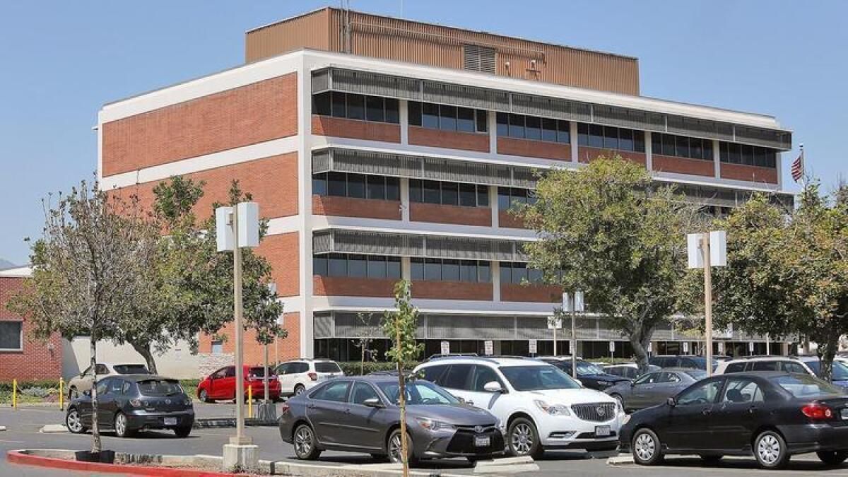 Commercial building with tan and white facade, windows, and parking spaces. Blue sky and greenery.