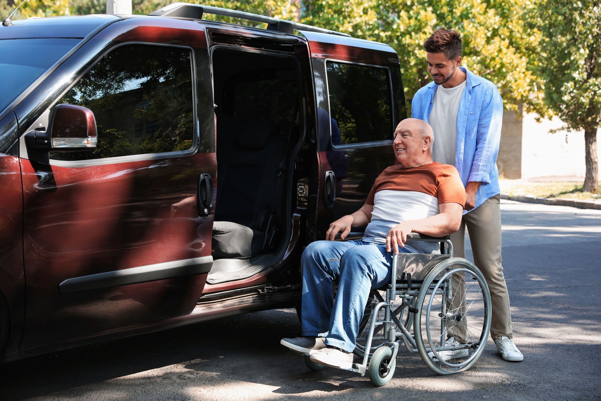 Man helping person in wheelchair enter accessible van.