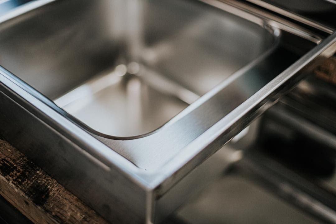 Un lavandino in acciaio inossidabile è appoggiato su un tavolo di legno.