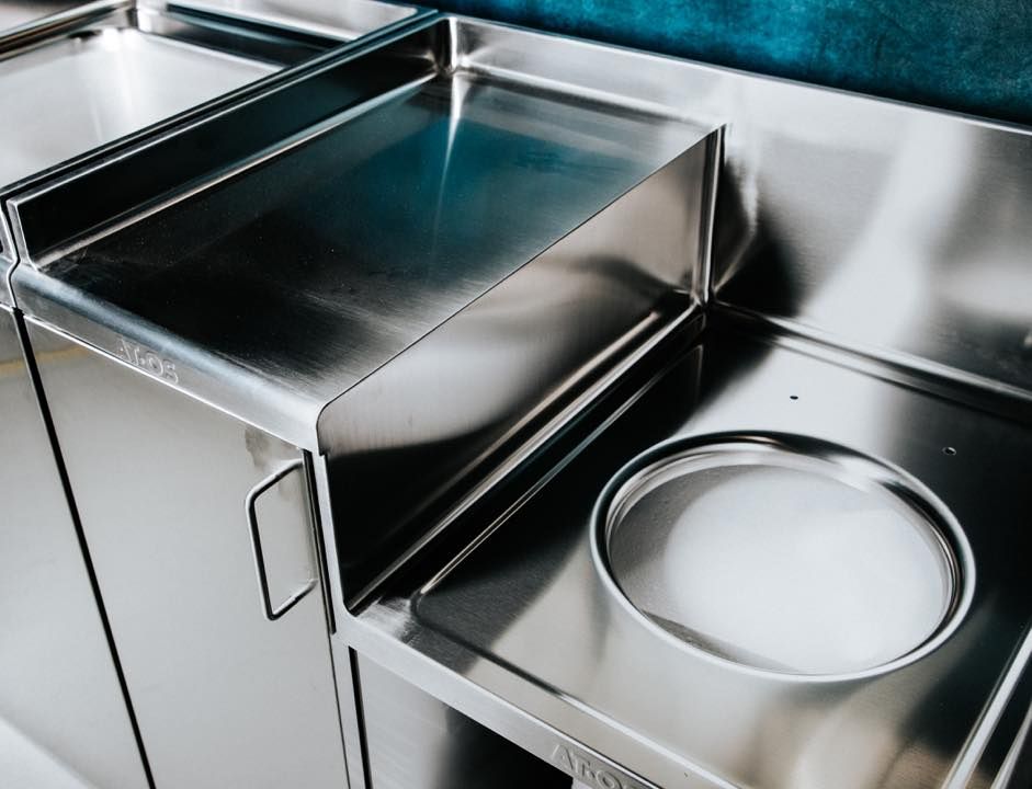 Un piano di lavoro in acciaio inossidabile con un cestino della spazzatura sottostante