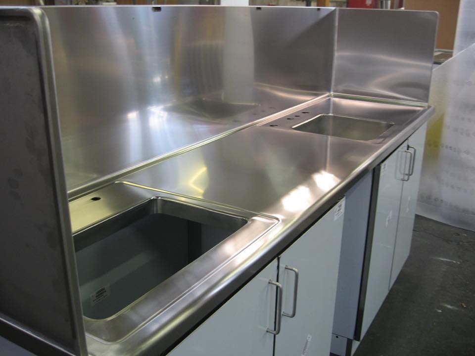 Un bancone da cucina in acciaio inossidabile con due lavelli e mobili