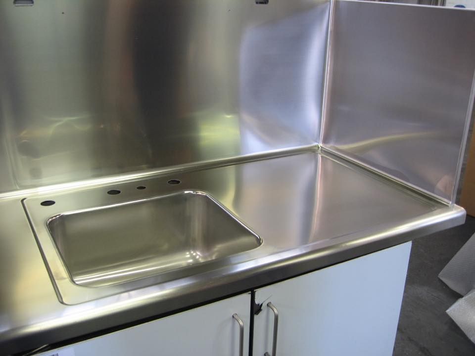 Un lavandino in acciaio inossidabile con un mobile bianco sottostante