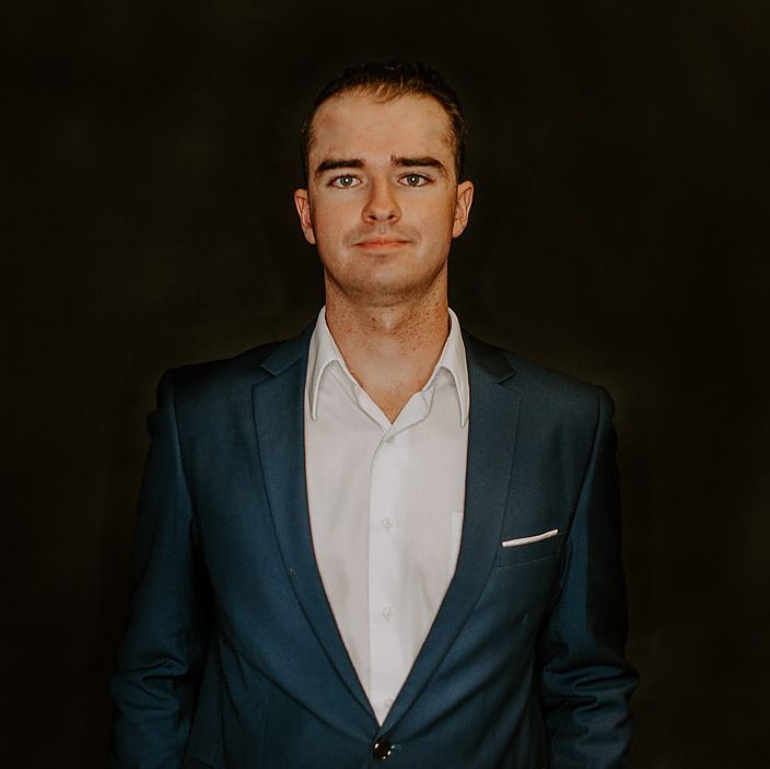 Headshot of Chris Degenaars in a suit against a dark backdrop