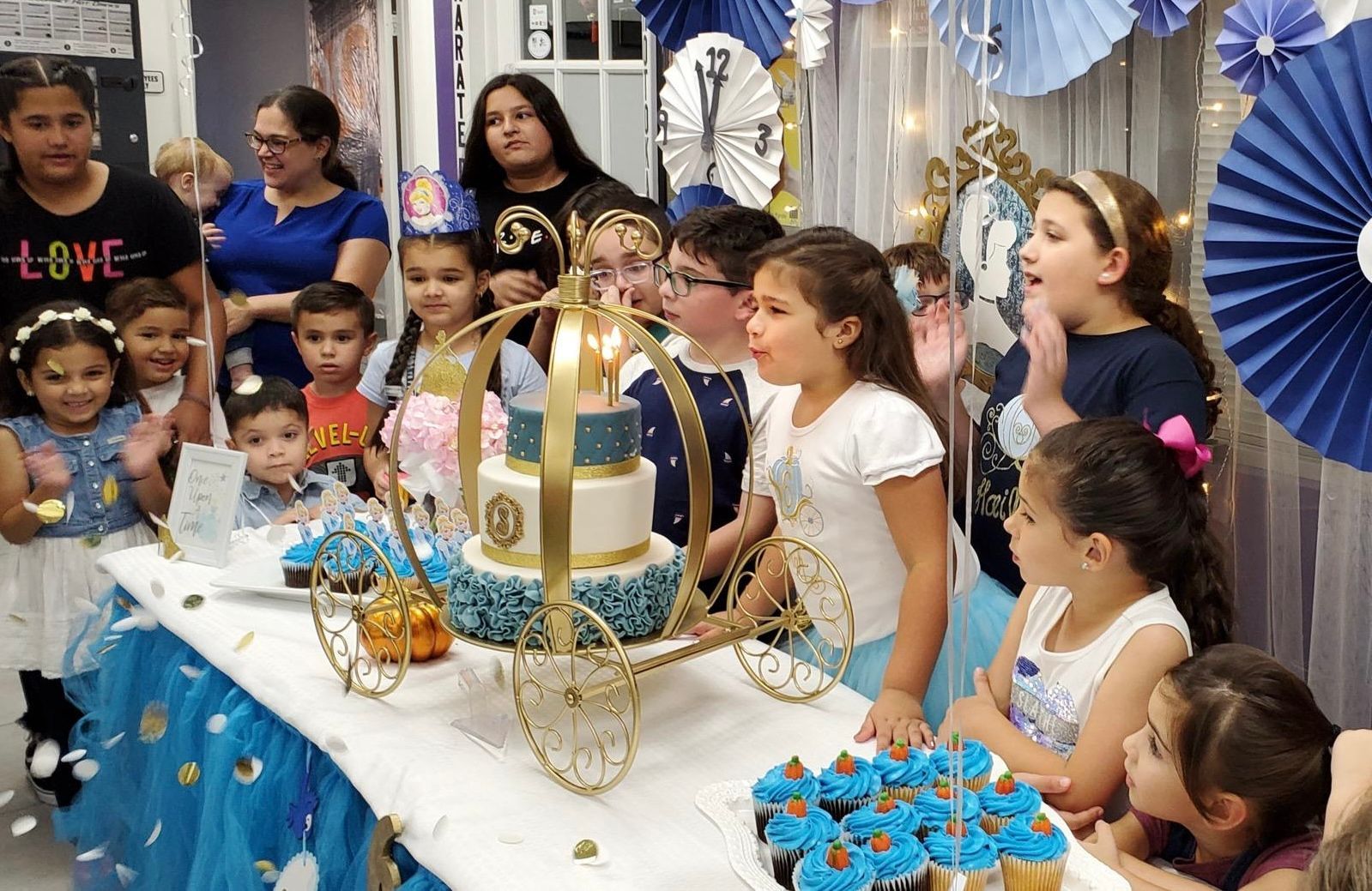 Un grupo de niños está sentado en una mesa con un pastel y pastelitos.