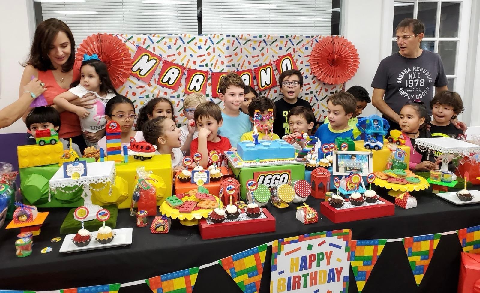 Un grupo de niños están de pie alrededor de una mesa en una fiesta de cumpleaños.