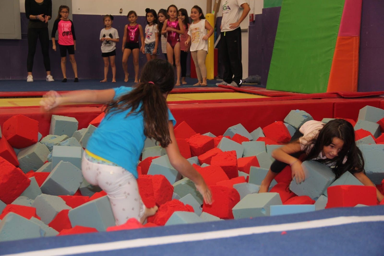 Un grupo de niñas está jugando en una piscina de cubos de espuma.