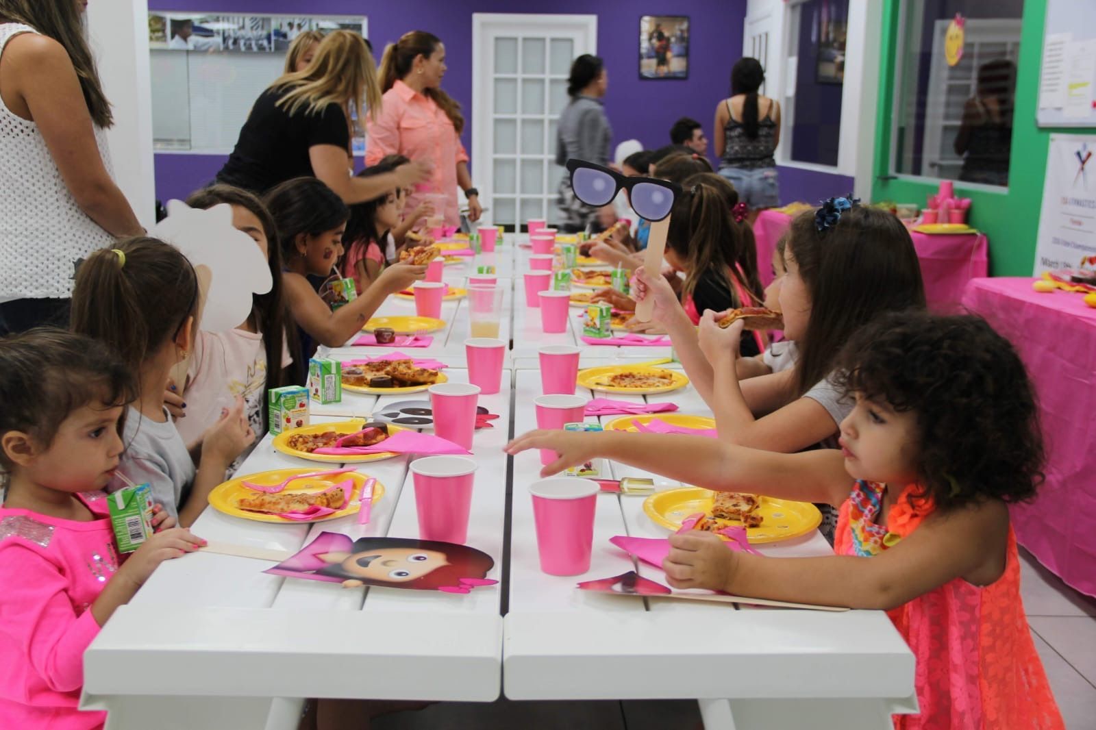 Un grupo de chicas jóvenes están sentadas en una mesa larga comiendo comida.