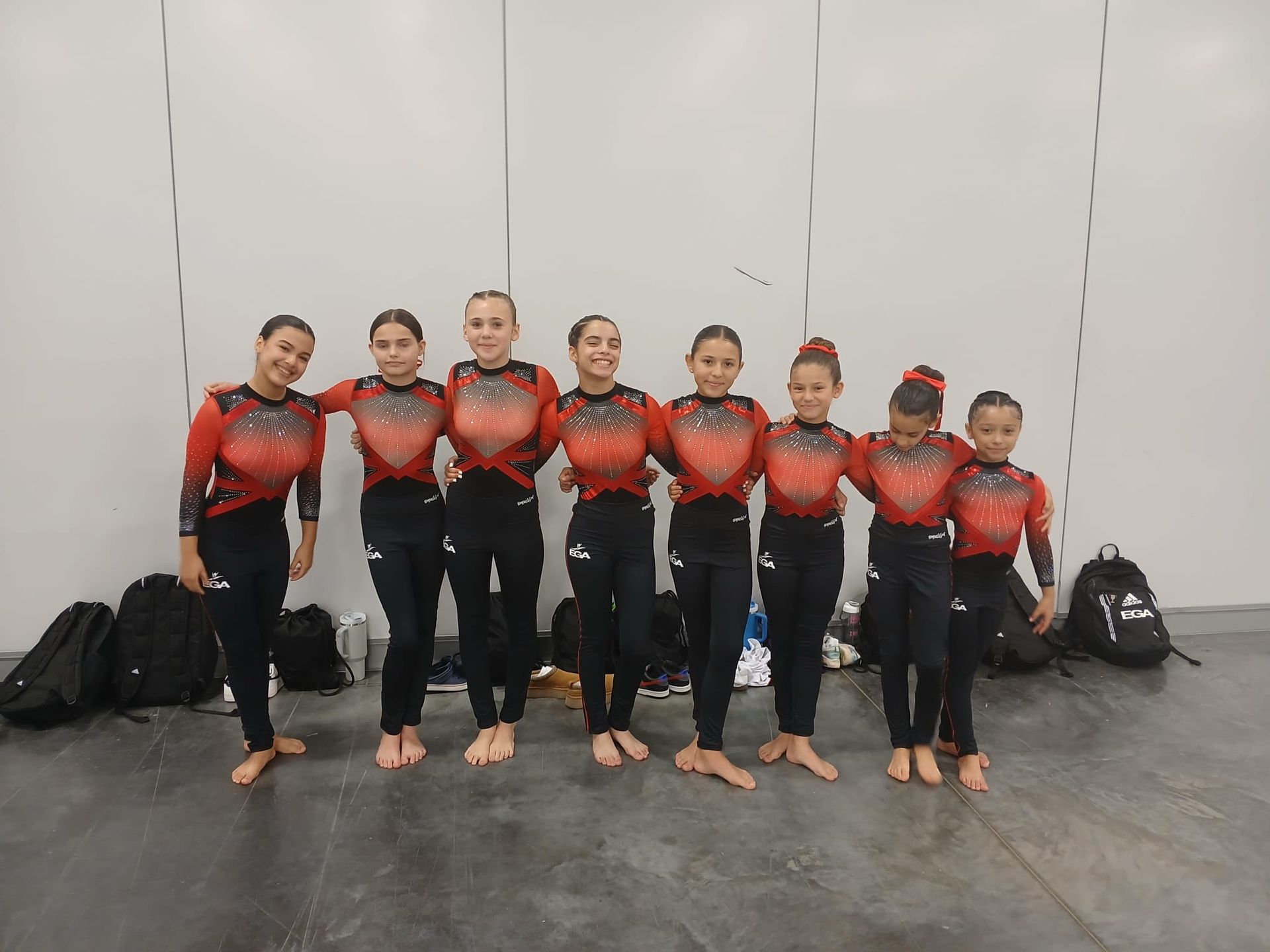 Un grupo de chicas jóvenes posan para una foto en un gimnasio.