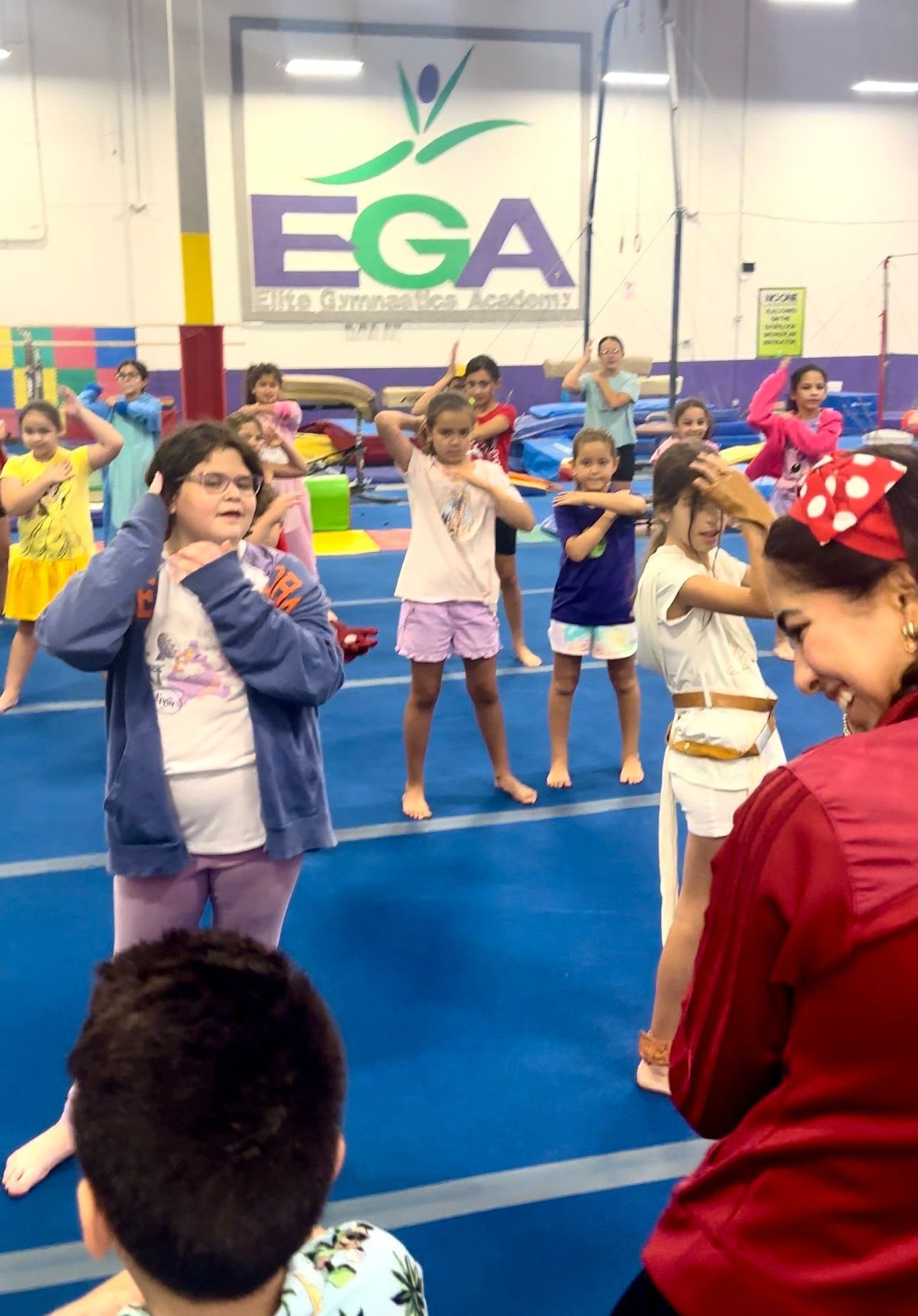 Un grupo de niños baila delante de un cartel que dice ega