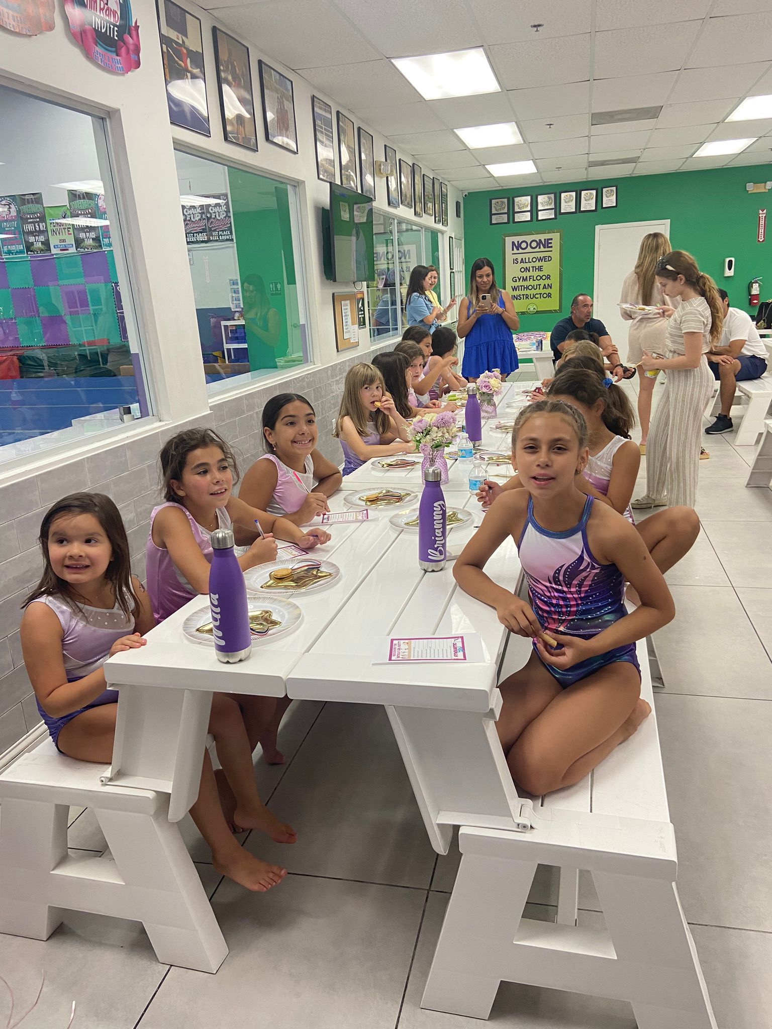 Un grupo de chicas jóvenes están sentadas en una mesa larga comiendo comida.