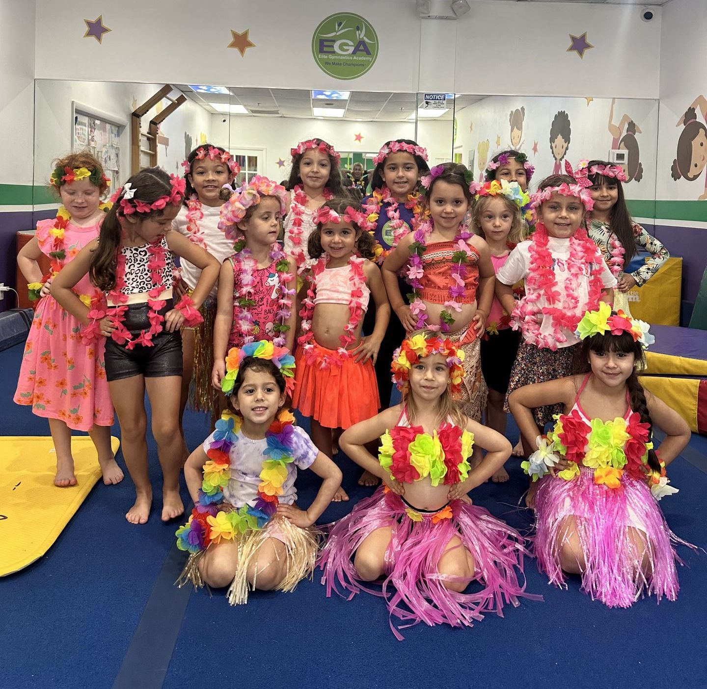 Un grupo de chicas jóvenes posan para una foto frente a un cartel que dice ega